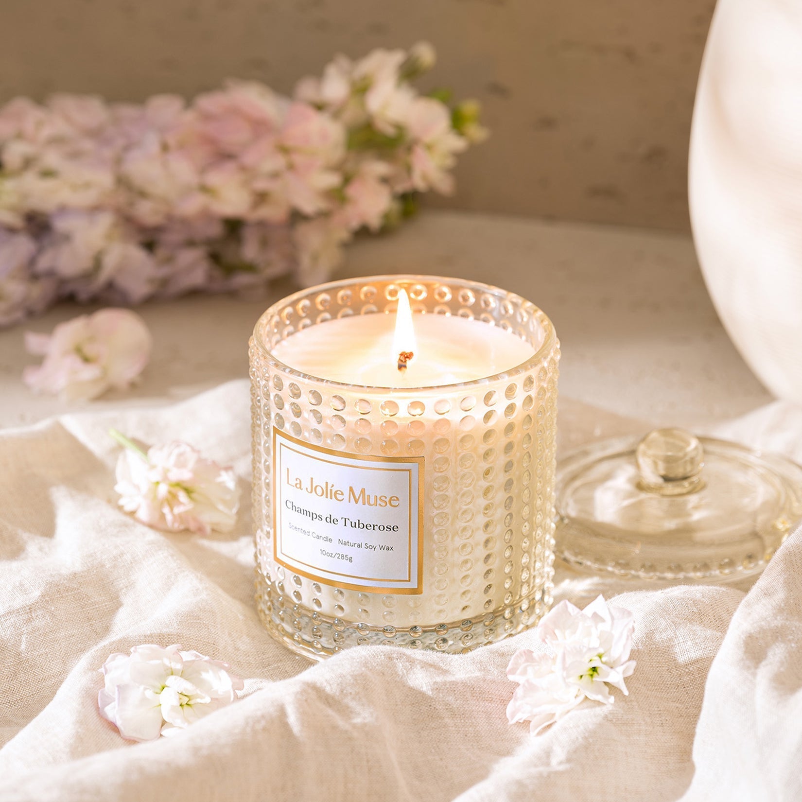 Burning candle with flower and cloth in background
