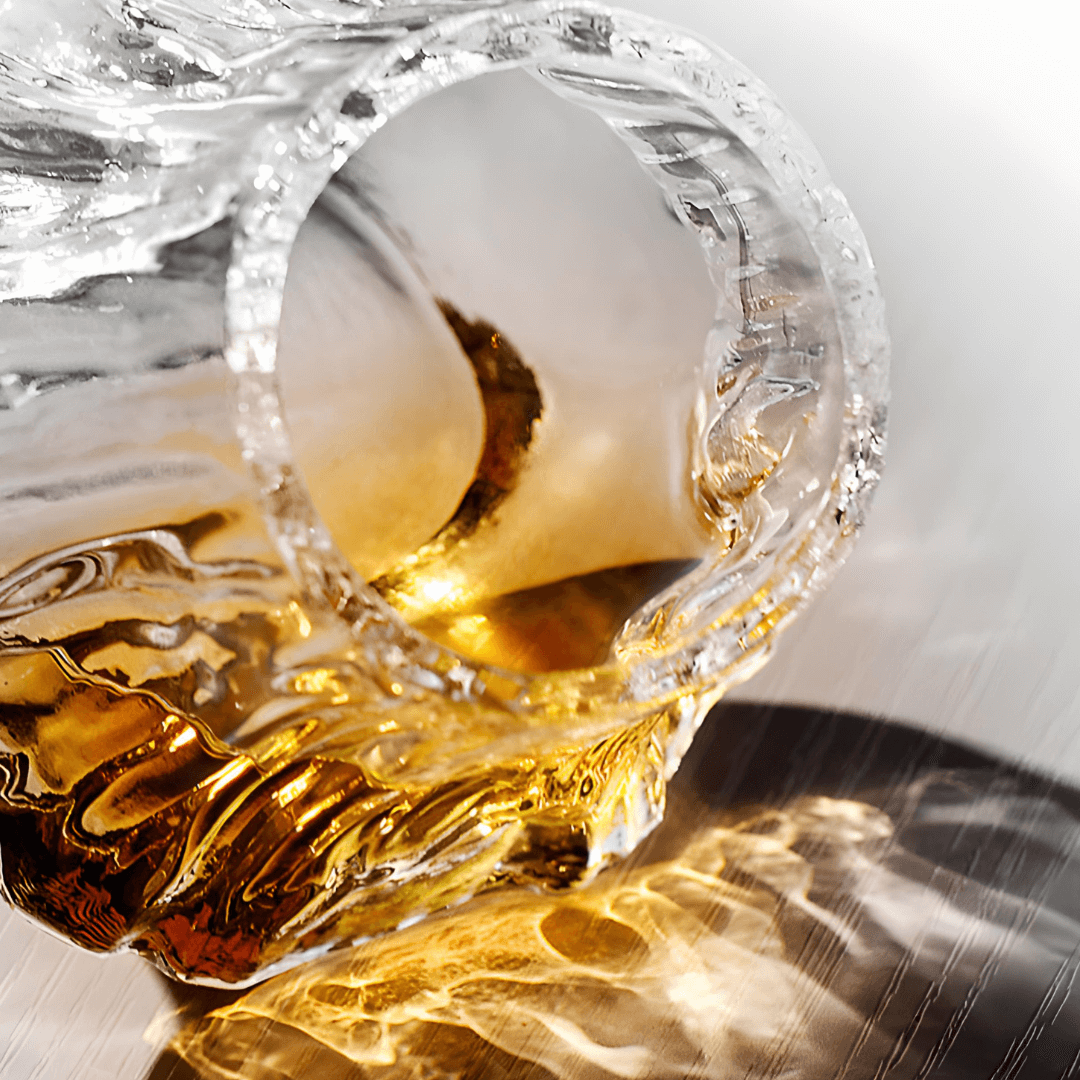 Liquid in a textured glass tilted on the side with reflection on surface.