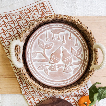 Decorative ceramic plate with embossed design on a woven tray