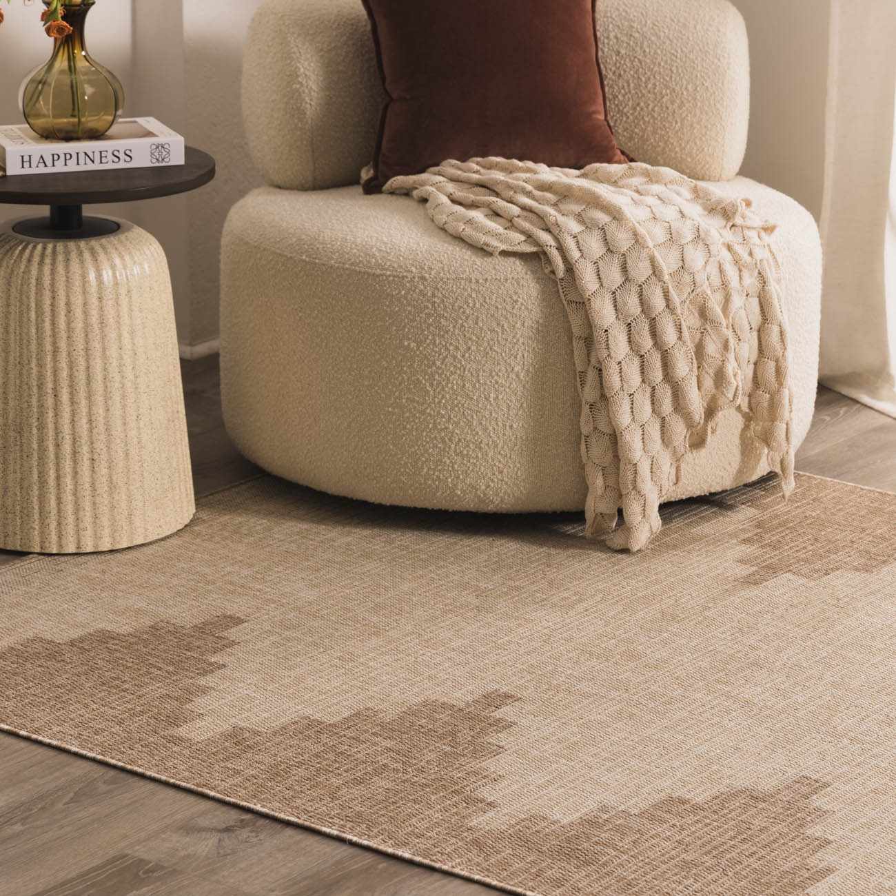 Brown cushion and blanket on a sofa with side table on a beige rug.