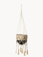 Macrame plant hanger with a woven design and tassels on a white background