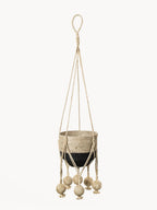 Woven plant hanger with decorative balls on a white background