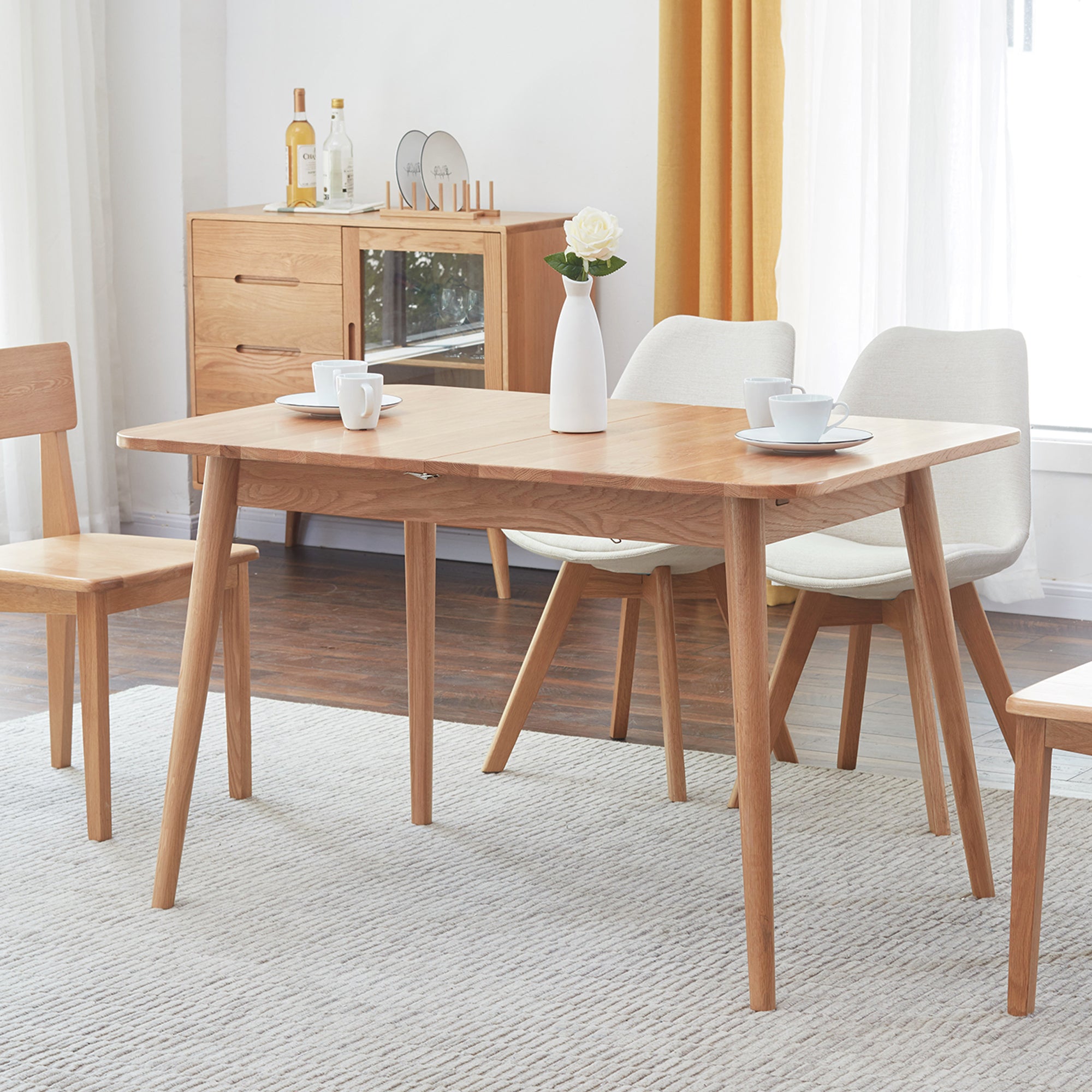Dining room with wooden table and chairs, white walls, and a window with yellow curtains.