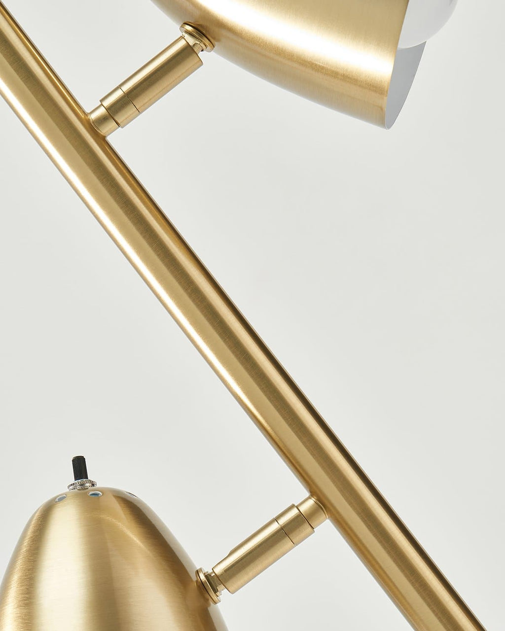 Close-up of a gold lamp with a white shade on a light gray background