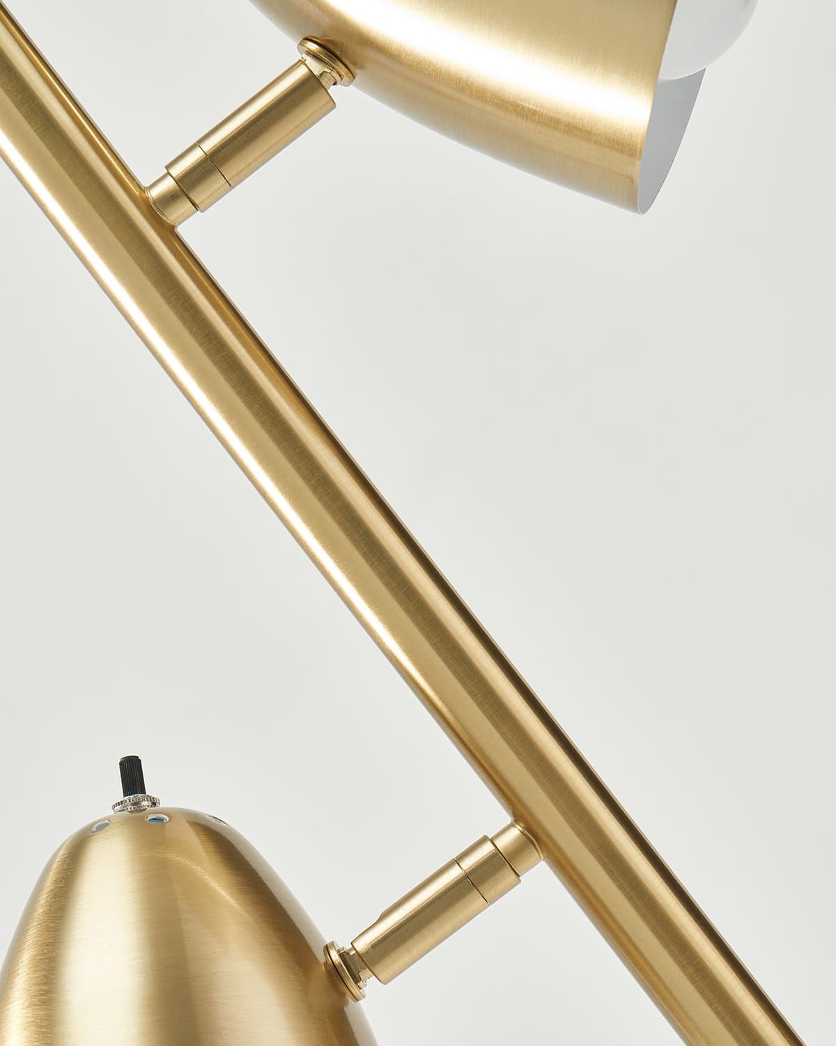 Close-up of a gold lamp with a white shade on a light gray background