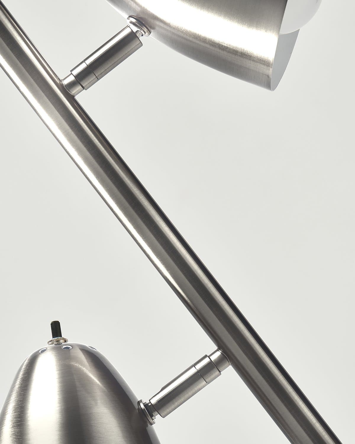 Close-up of a modern floor light fixture with metallic finish on a gray background