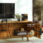 Wooden TV stand with soft-close door hinge mechanism, TV, and decor items.