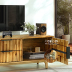 Wooden TV stand with a television, speakers, and decorative items in a room.