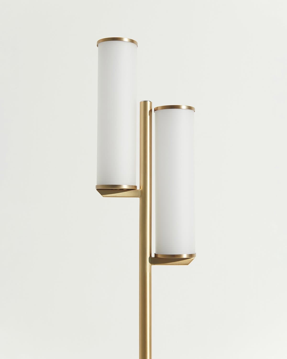 Light fixture with white cylindrical shades and gold metal accents on a light gray background