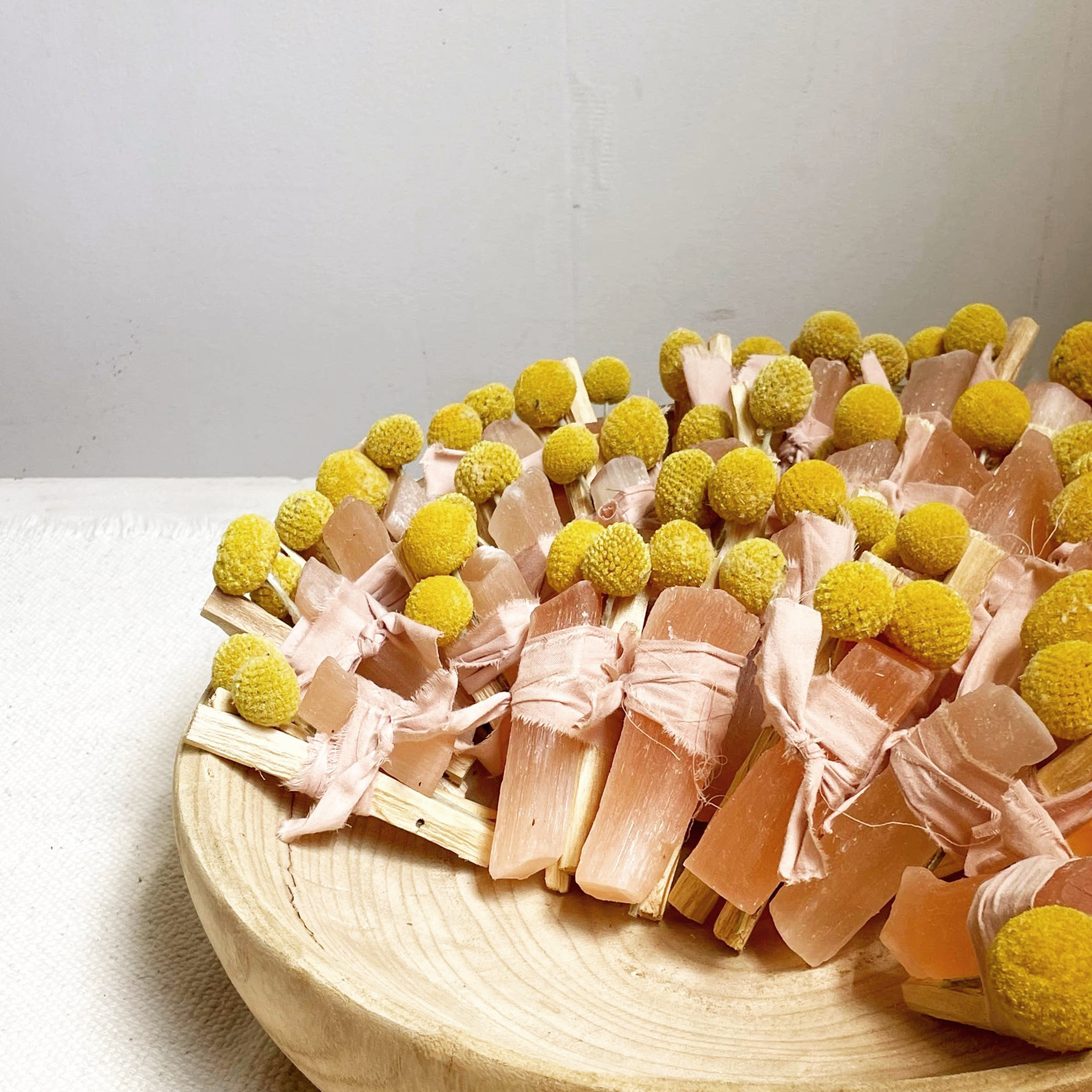 Decorative item with pink ribbons and yellow spherical decorations on a wooden surface.