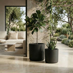 Two black planters with green plants on a patio with a modern outdoor furniture set.