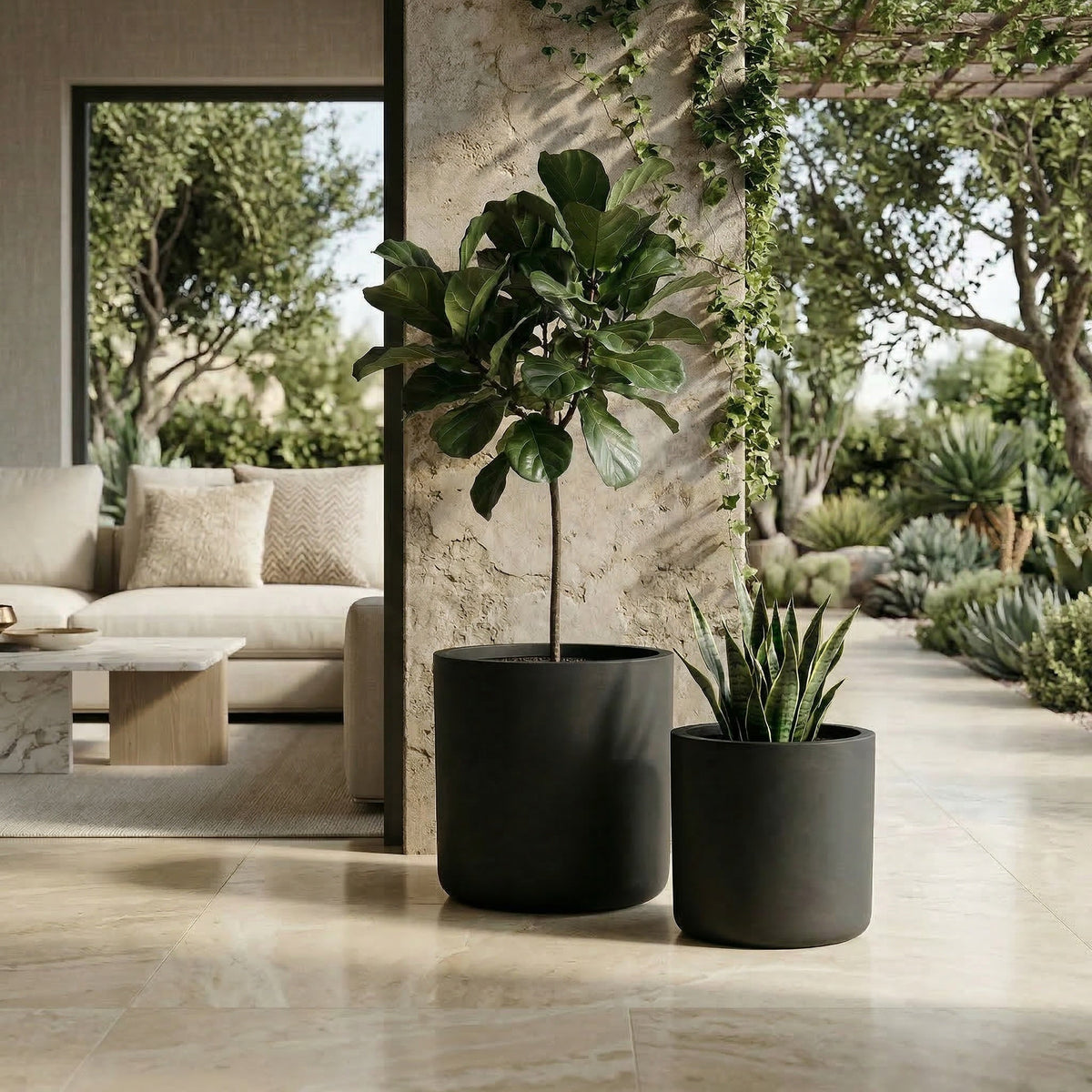 Two black planters with green plants on a patio with a modern outdoor furniture set.