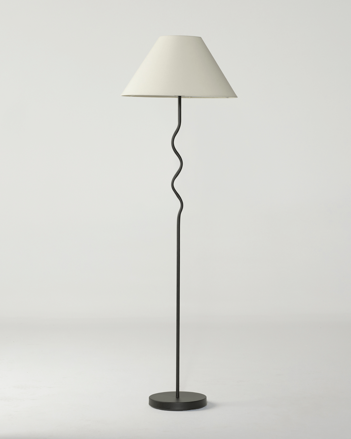 Floor lamp with a white shade and black base on a light gray background