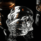 Clear glass skull-shaped drinkware on a dark background