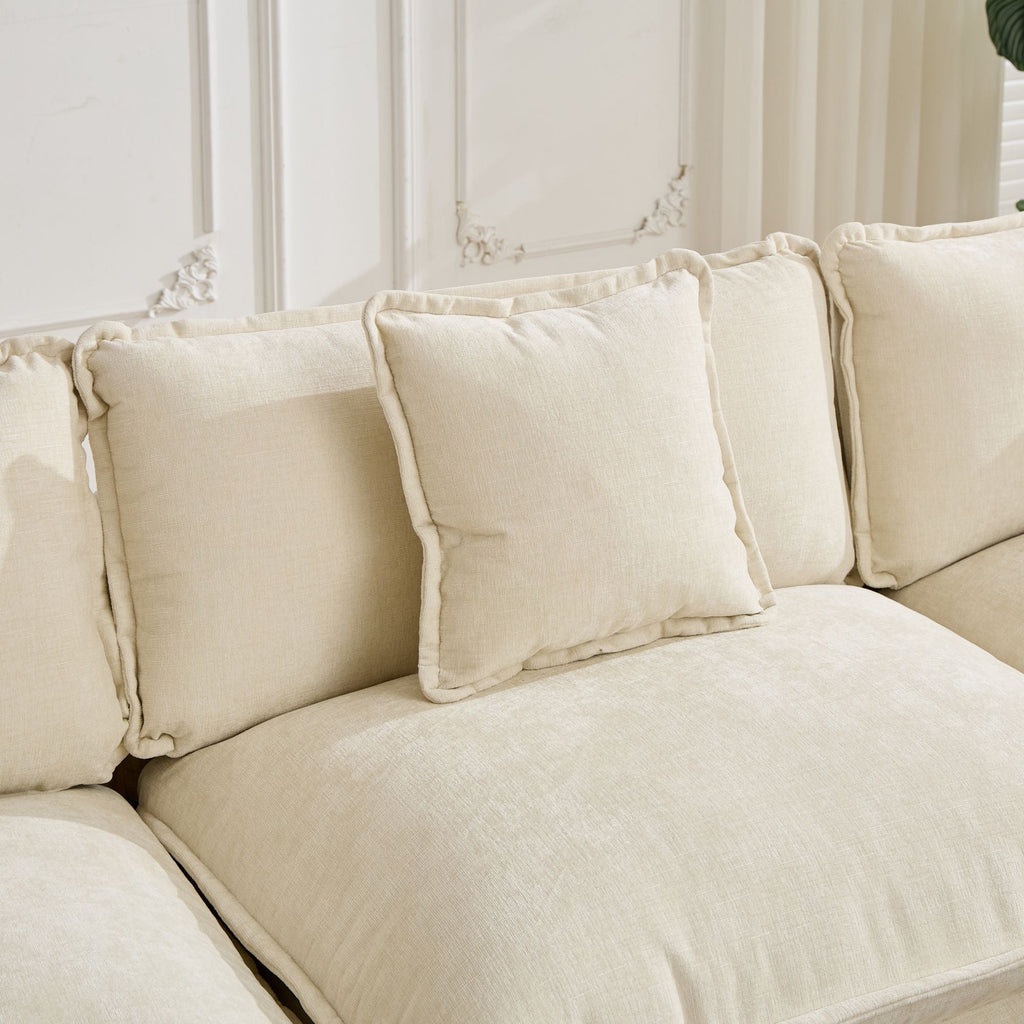 Beige sectional sofa with decorative pillows against a neutral wall.