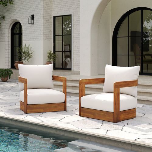 Two wooden chairs with white cushions on a patio by a poolside.