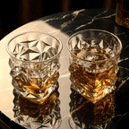 Two crystal glasses filled with whiskey on a reflective surface