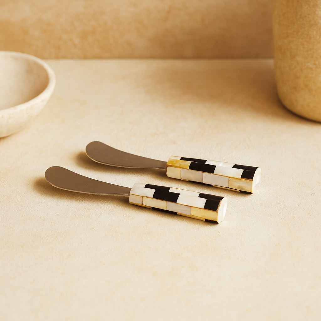 Two decorative knives with black and white patterned handles on a beige surface