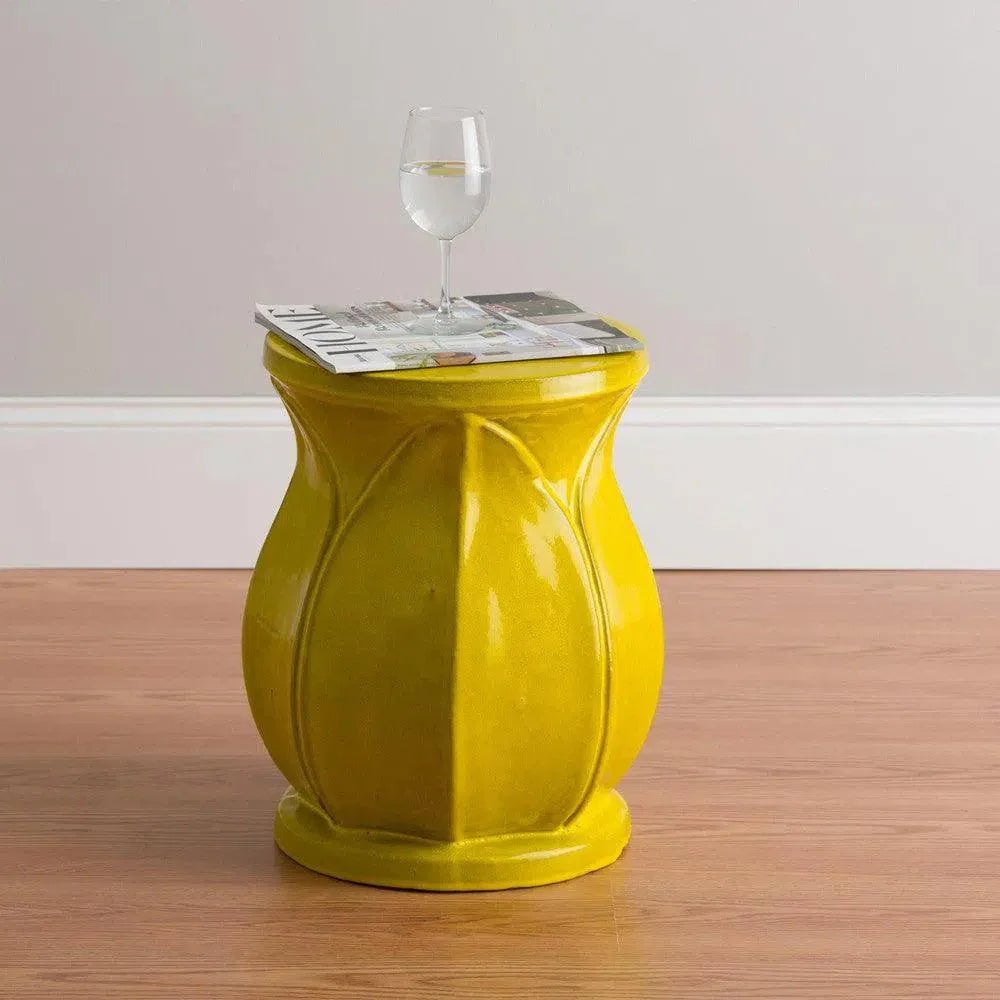 Yellow side table with a glass of wine and magazine on a wooden floor.