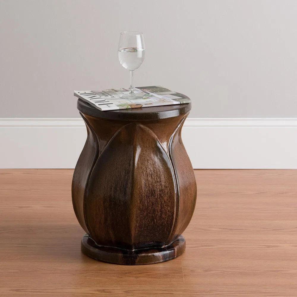 Wooden side table with a glass of water and magazine on top against a plain wall.