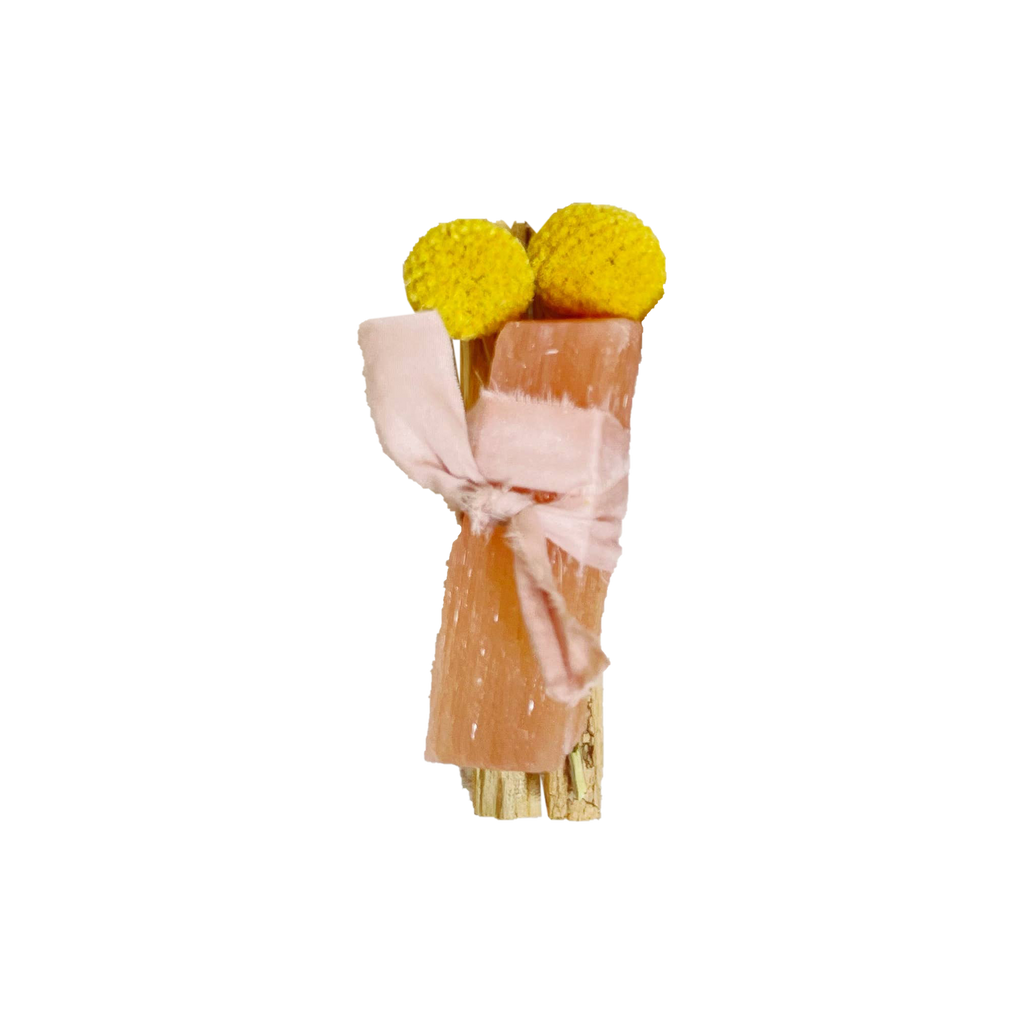 Two yellow pom-poms tied with a pink ribbon on a white background