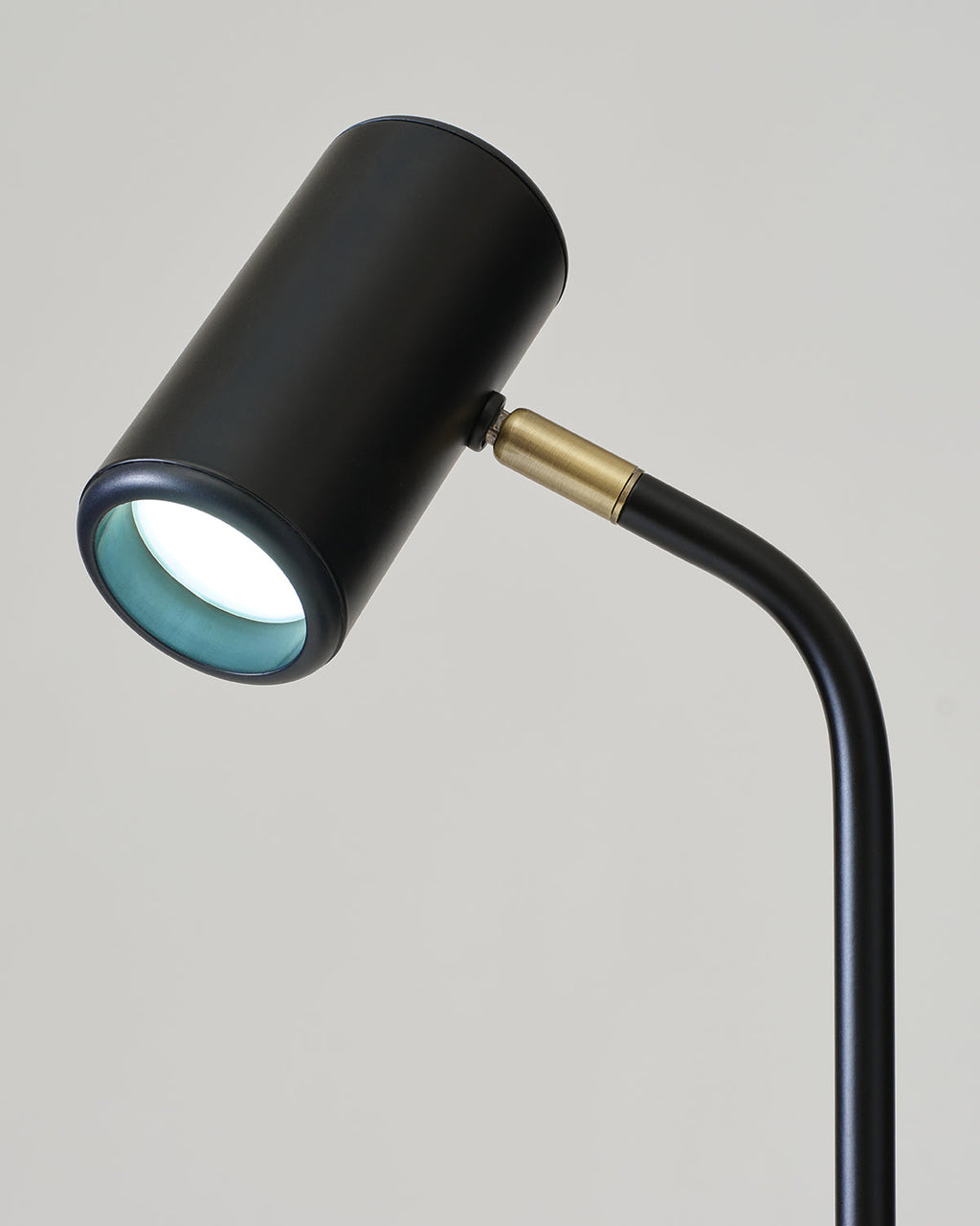 Black and gold lamp with a white light bulb on a gray background