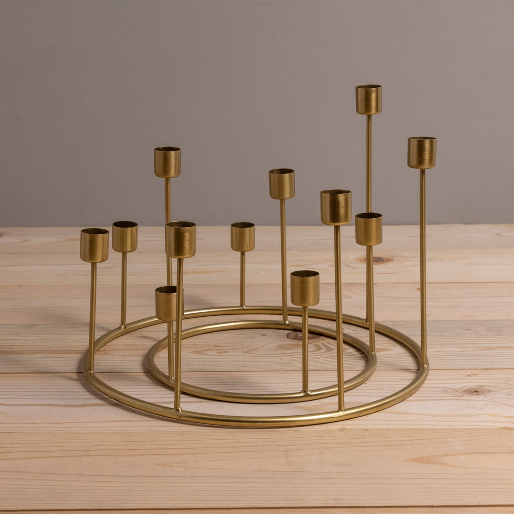 Gold metal candle holder with multiple small candles on a wooden surface