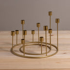 Gold metal candle holder with multiple small candles on a wooden surface