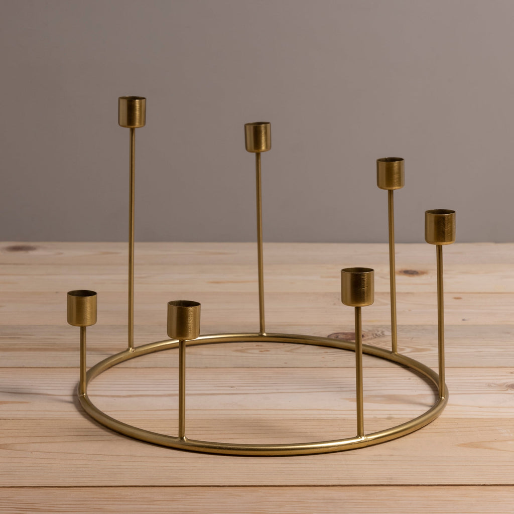 Gold candle holder with multiple small candle holders on a wooden surface