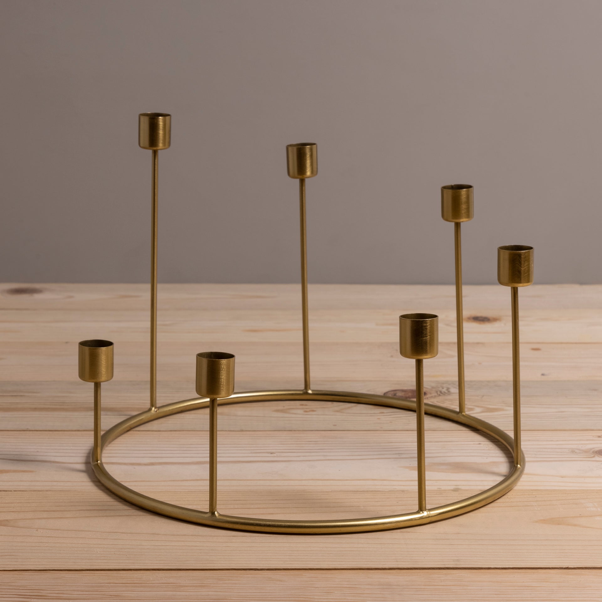 Gold candle holder with multiple small candle holders on a wooden surface