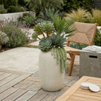Potted succulents on a patio with a chair and table in the background
