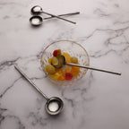 Glass bowl with fruits and measuring spoons on a marble surface