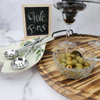 Olive bar setup with olives in a glass bowl on a wooden board, accompanied by a sign reading 'Olive Bar'.