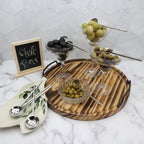 Wooden tray with bowls of olives and olive-themed decor on a marble surface.