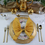 Elegant table setting with gold teapot, plates, and cutlery on a white tablecloth.