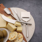 Cheese platter with cheese, crackers, and cheese tools on a gray surface