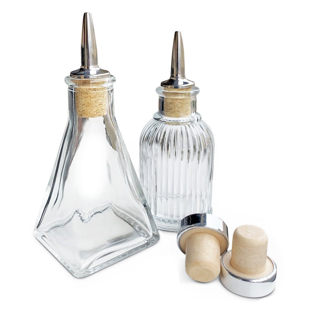 Two glass condiment bottles with wooden and metal caps on a white background