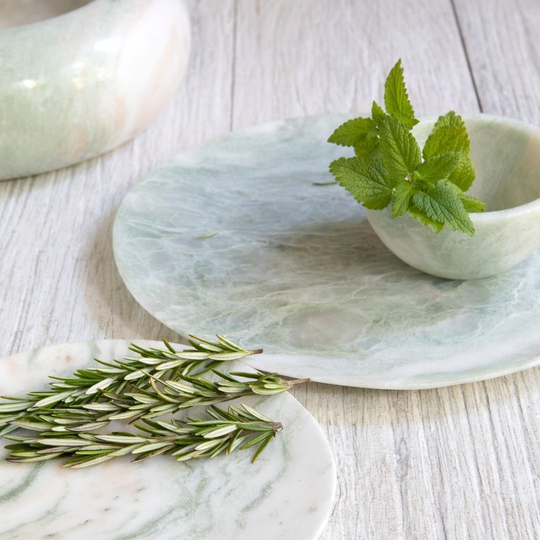 Marble coasters with greenery on a light wooden surface