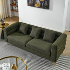 Green sofa in a living room setting with a rug and side table.