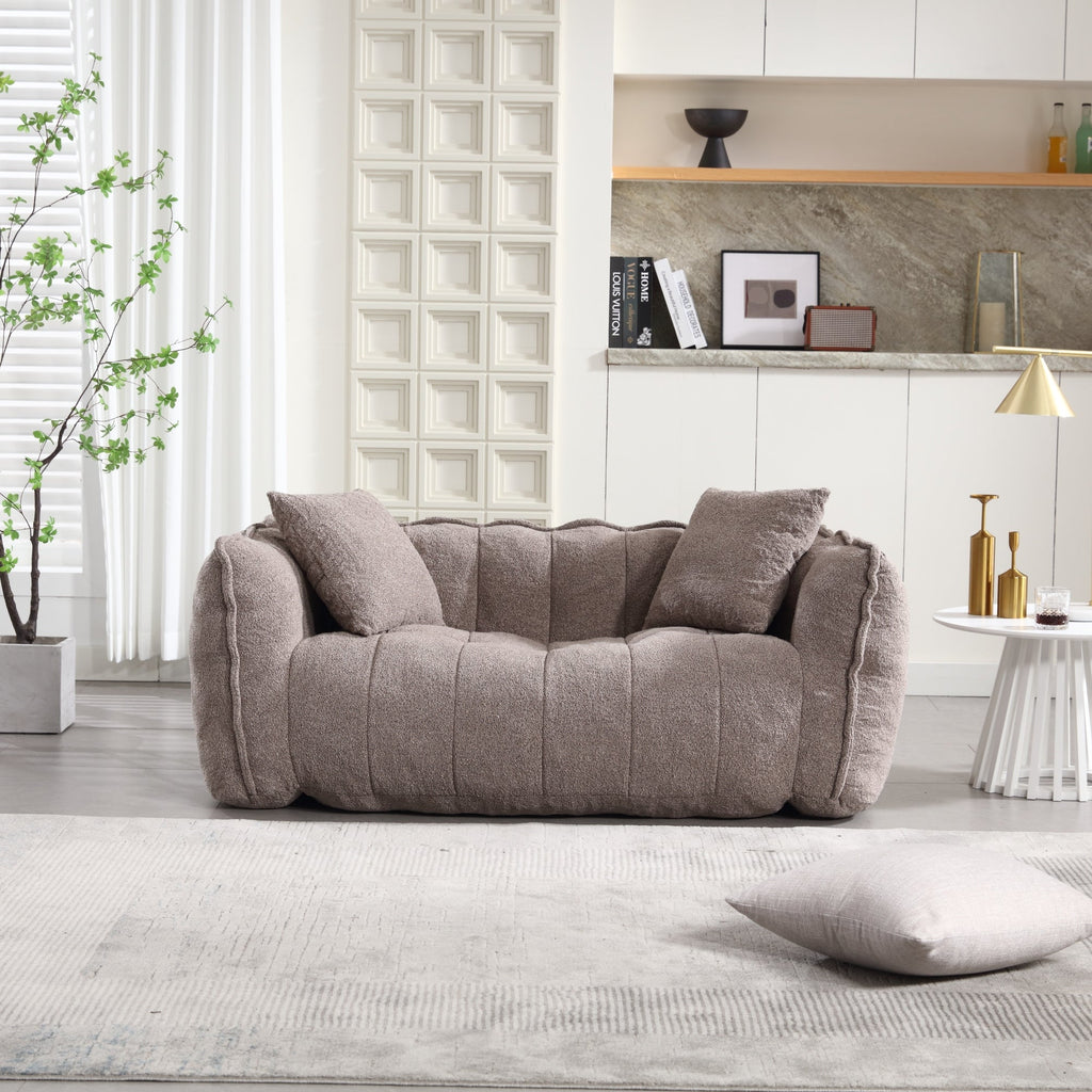 Gray sofa in a modern living room with a plant and shelves in the background.