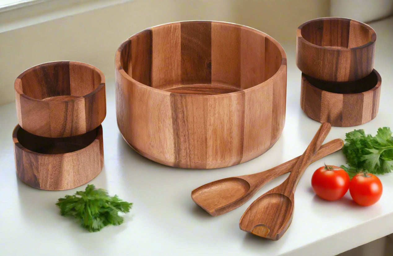 Wooden kitchenware set including a bowl, cups, and spoons on a white surface with vegetables.