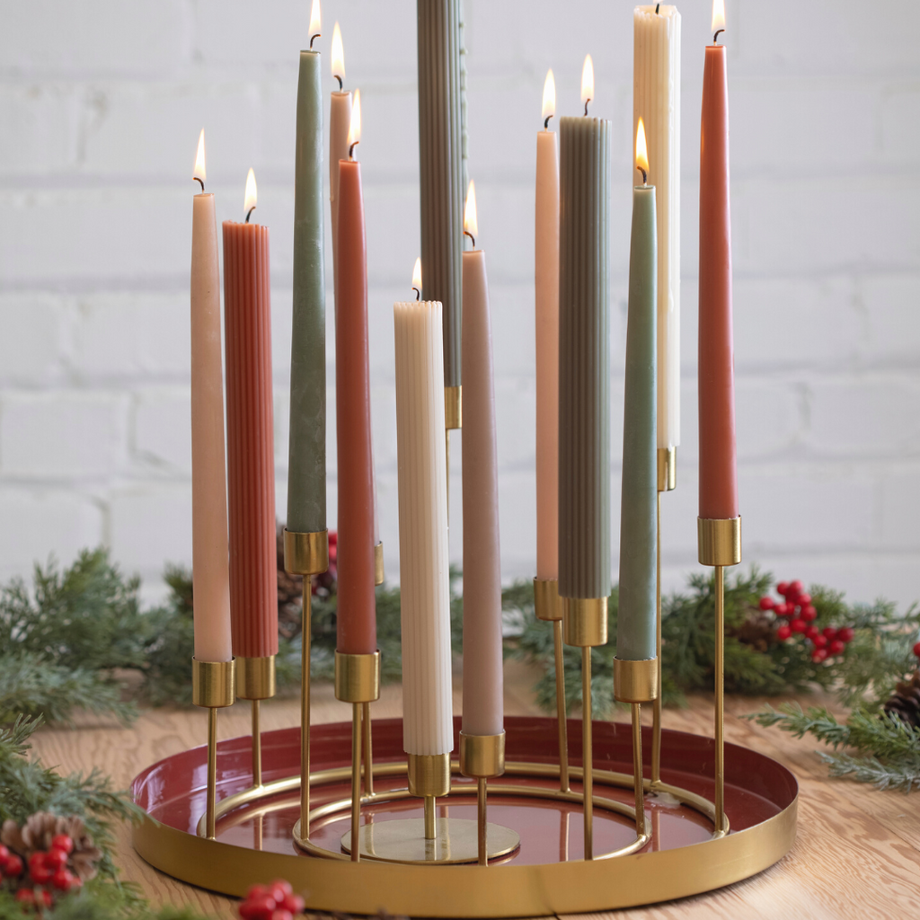 Decorative candle holder with lit candles on a wooden surface with a white brick wall background.