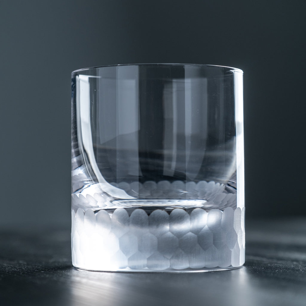 Clear whiskey glass with honeycomb pattern on a dark background