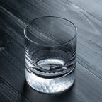Clear glass with a textured base on a dark wooden surface