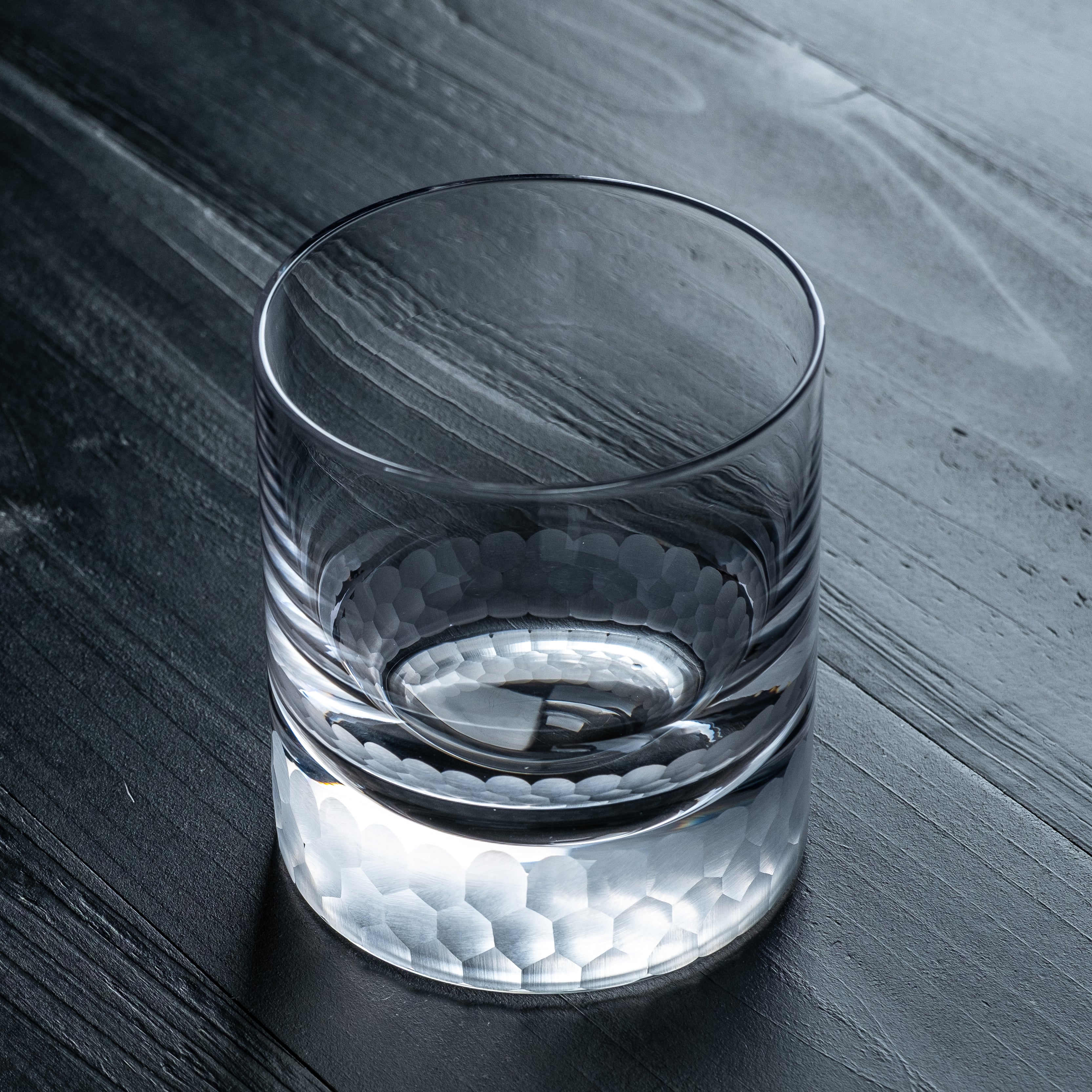 Clear glass with a textured base on a dark wooden surface