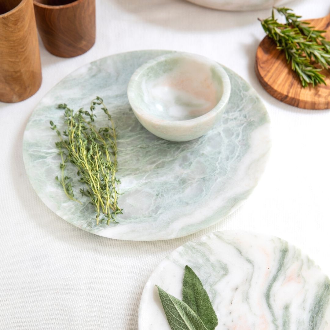 Marble coasters with herbs on a white surface