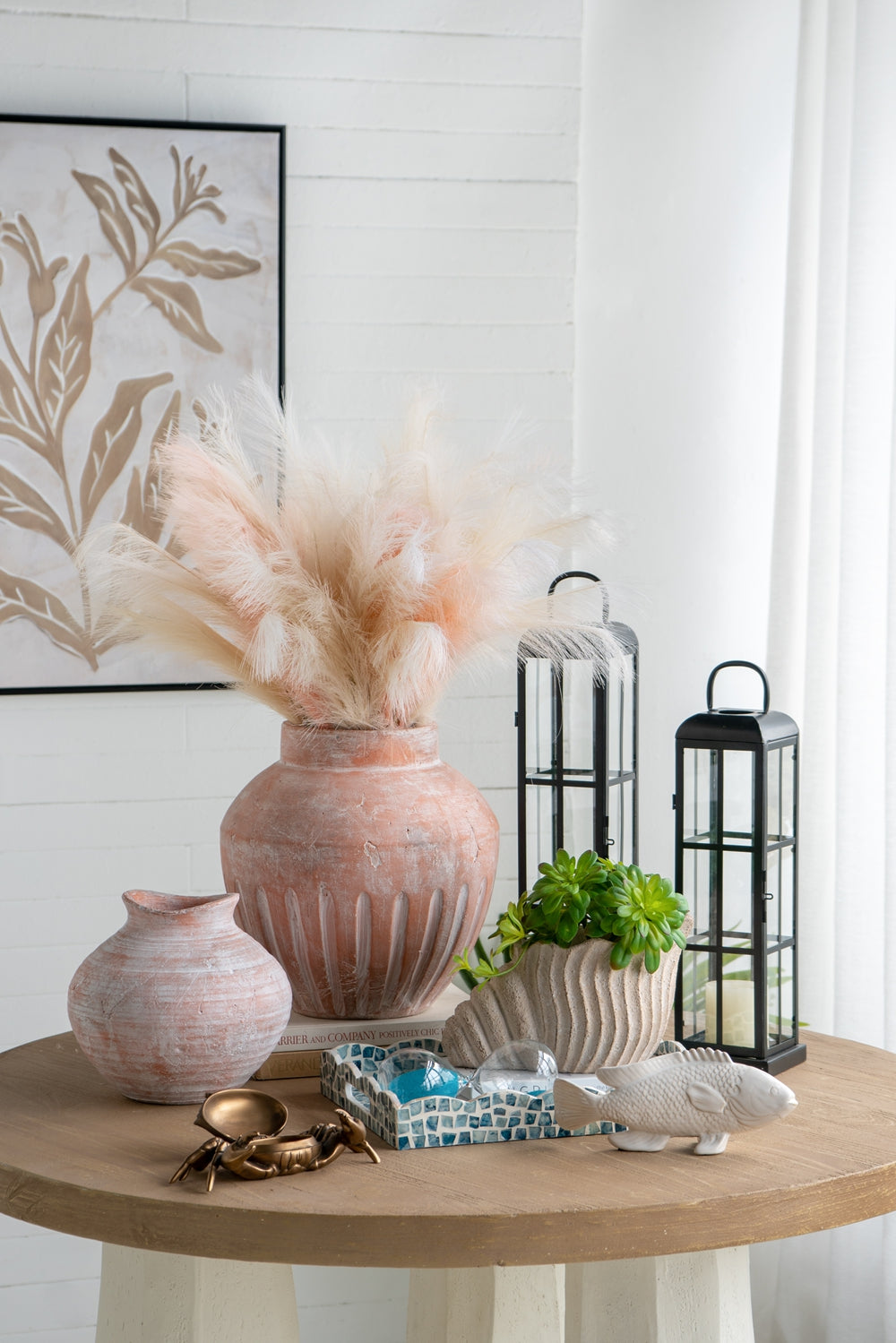 Decorative table setting with vases, lanterns, and a fish figurine in a home interior.