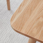 Close-up of a wooden table with a light wood finish on a textured gray surface.