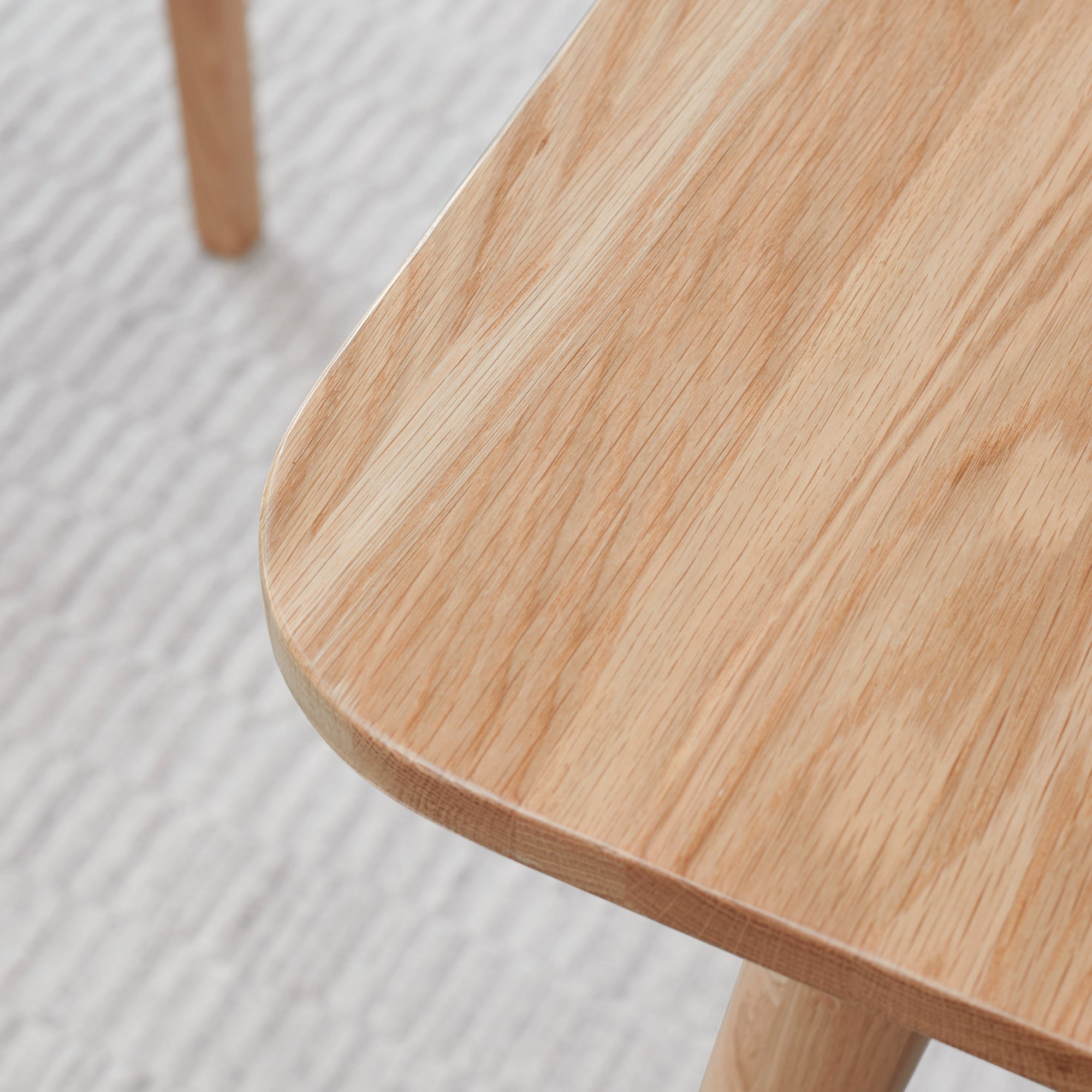 Close-up of a wooden table with a light wood finish on a textured gray surface.