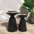 Two black side tables with a plant and items on a wooden deck.